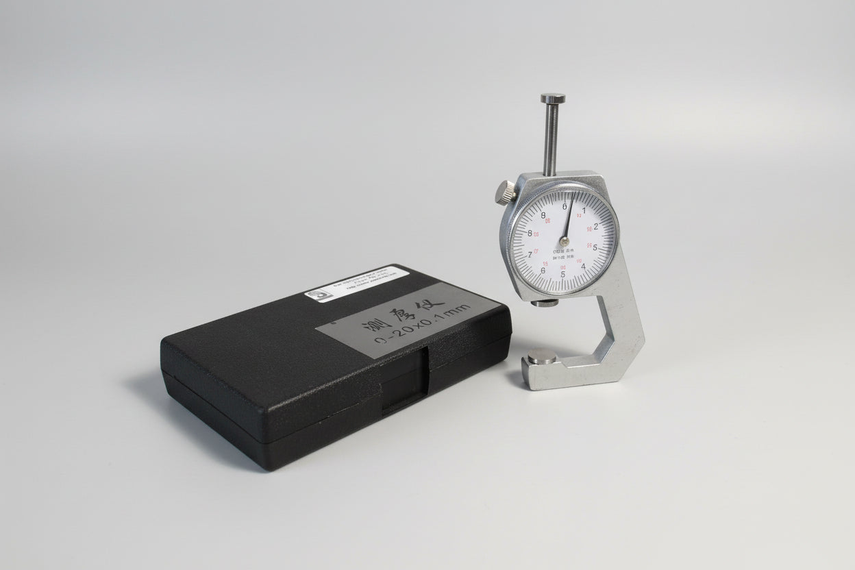 Dial indicator and black case on a wooden surface with a white background